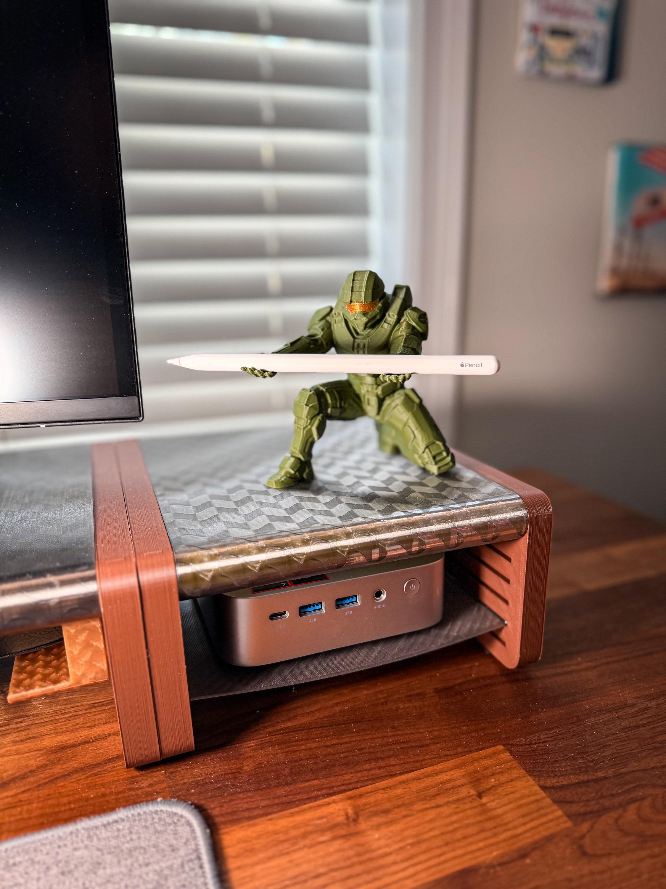 Green superhero figurine on a desk with a computer setup